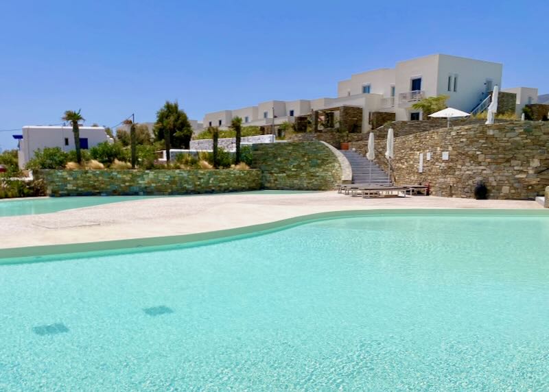 White Cycladic-style buildings rising above a sparkling free-form turquoise pool