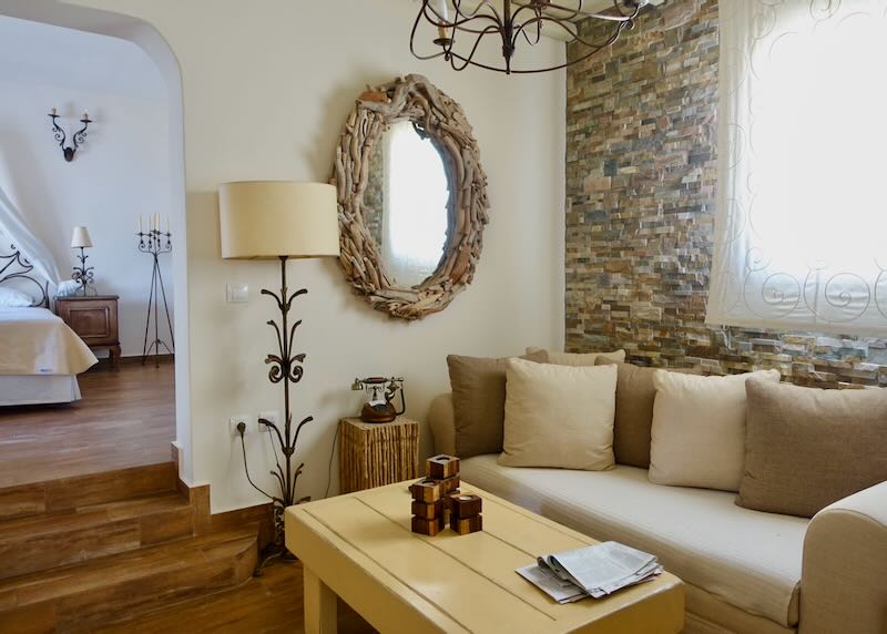 Tastefully Cycladic-styled living room, with open doorway providing a glimpse of a spacious bedroom beyond