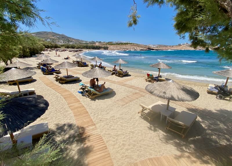 Sandy beach with wooden walking paths leading past thatched umbrellas