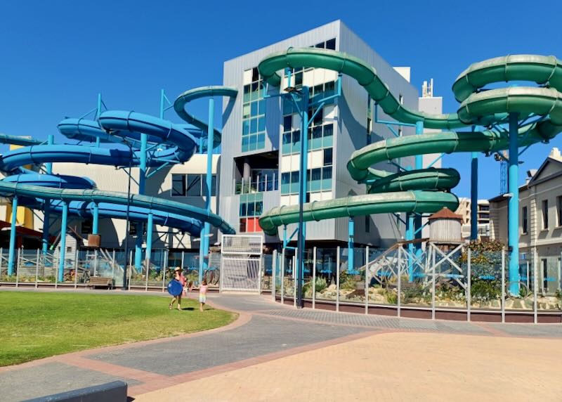 Waterslides burst out of a multi-level gray building like tentacles.