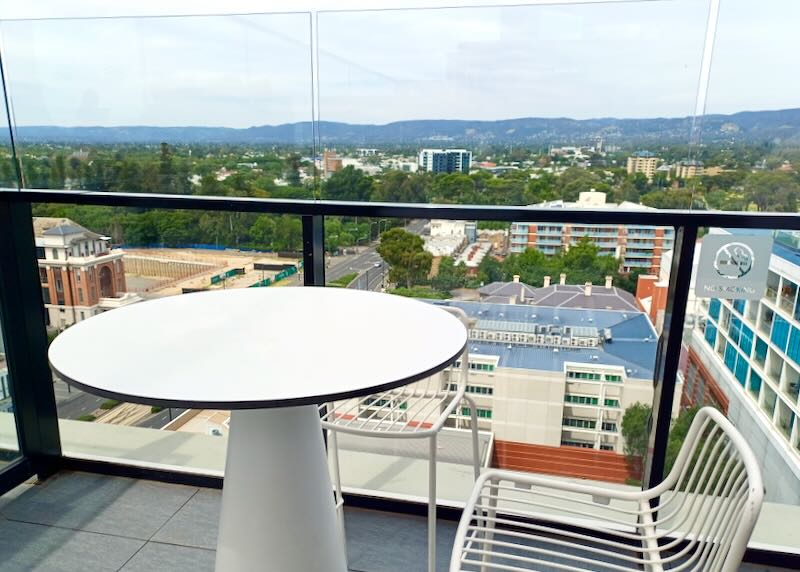 A table sits on a rooftop bar overlooking views of the city.