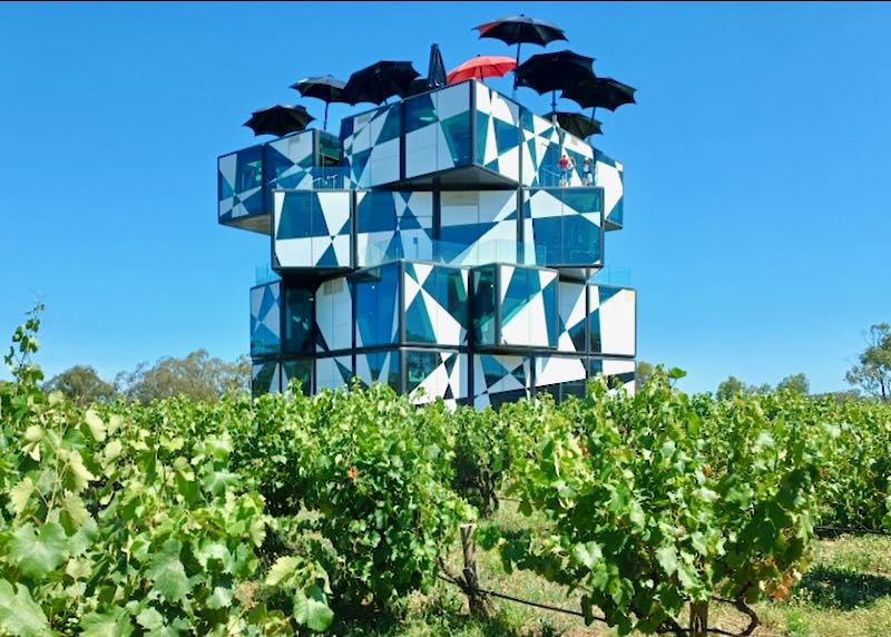 A building in a wine field has black and white square rooms that look like a cube.