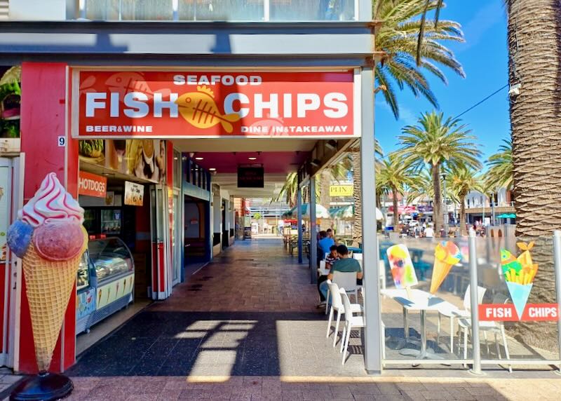 A red sign reads, "Fish Chips," next to a row of food stalls.