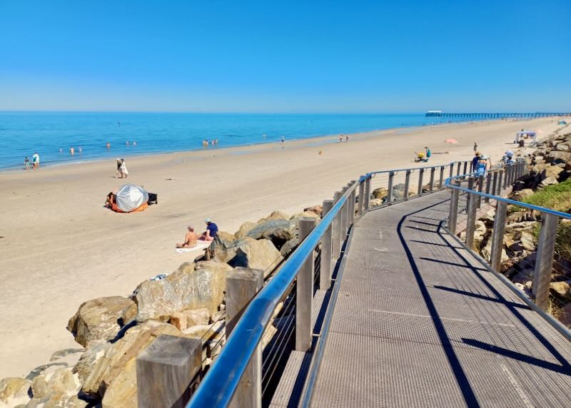 A metal ramp slopes down to the sand and the beach.