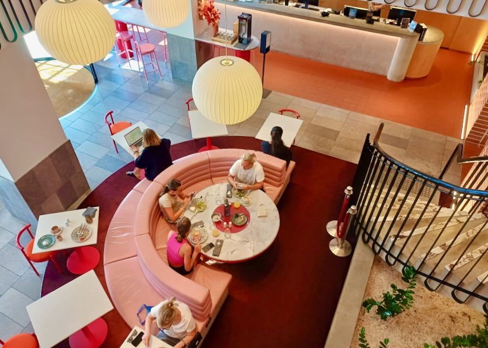 Looking down at people sitting at a pink round booth with seats on both sides.