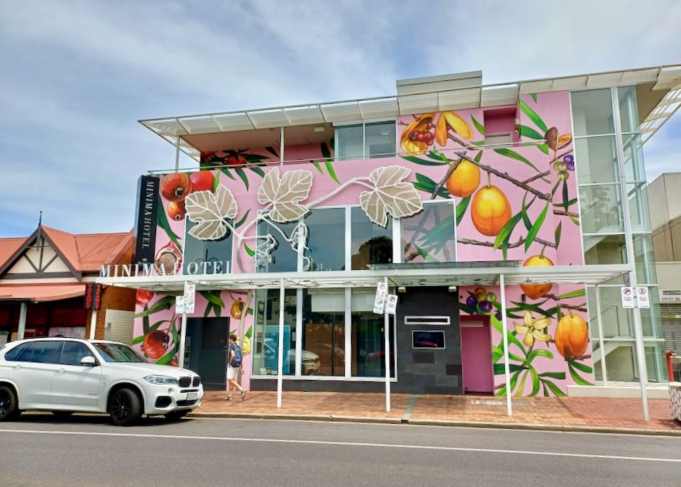 The exterior of a hotel with a pink and fruit tree mural.