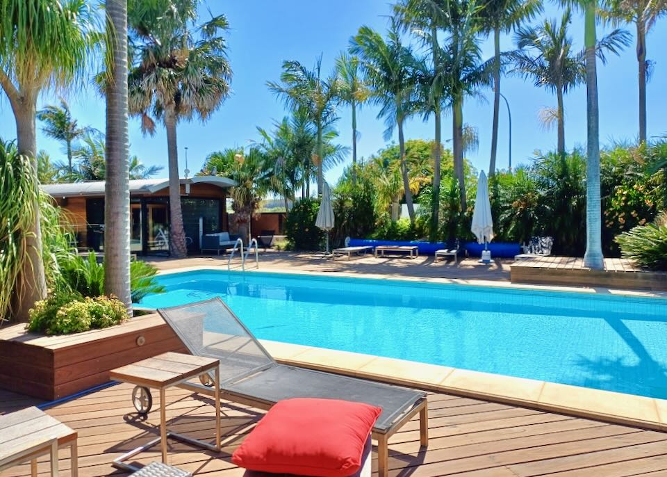 A lounge chair sits in the sun by a pool.