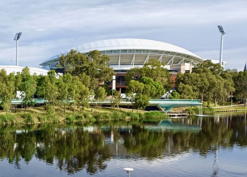 A rounded roof stadium sits next to a green river.