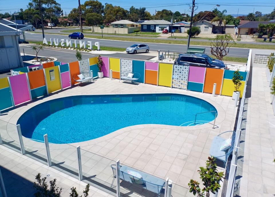 A retro outdoor pool has bright pink, blue, yellow, and orange panels next to it.