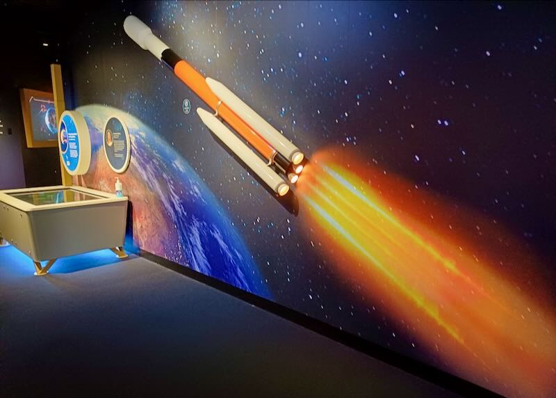 A wall with a space ship exhibit looks like it's flying into space with an orange jet stream.