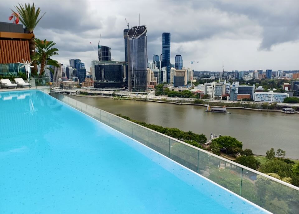 A blue pool overlooks a river and city skyline.