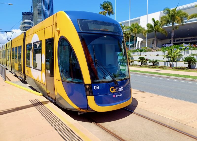 A yellow and blue tram pulls into a station.