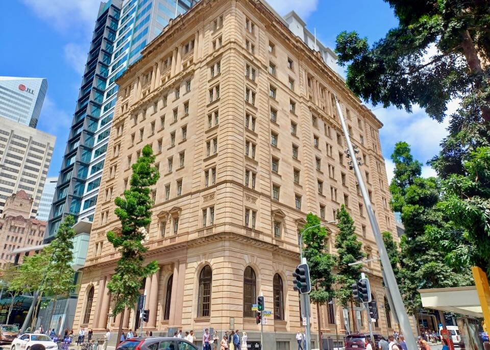 A tall tan stone building rises to the sky.