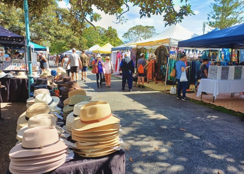 People walk through stalls at an open-air market.