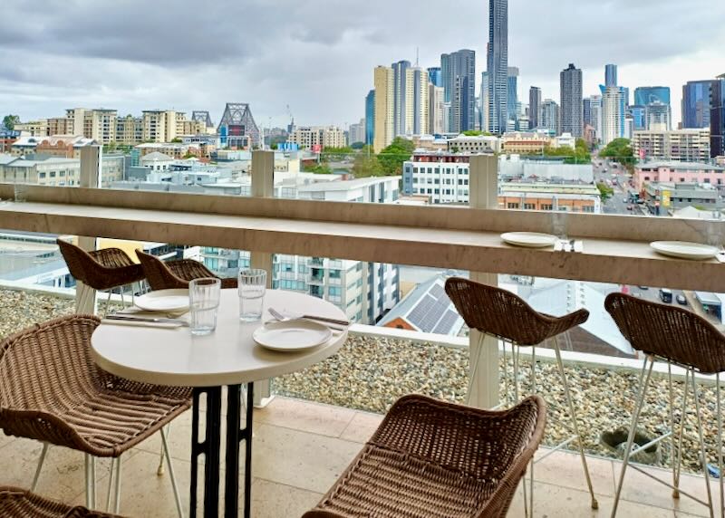 Brown whicker chairs sit overlooking a cityscape.