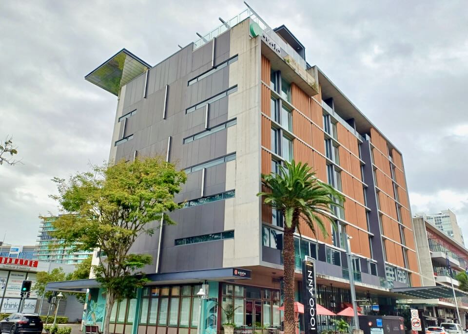 A seven story building has a palm tree out front.