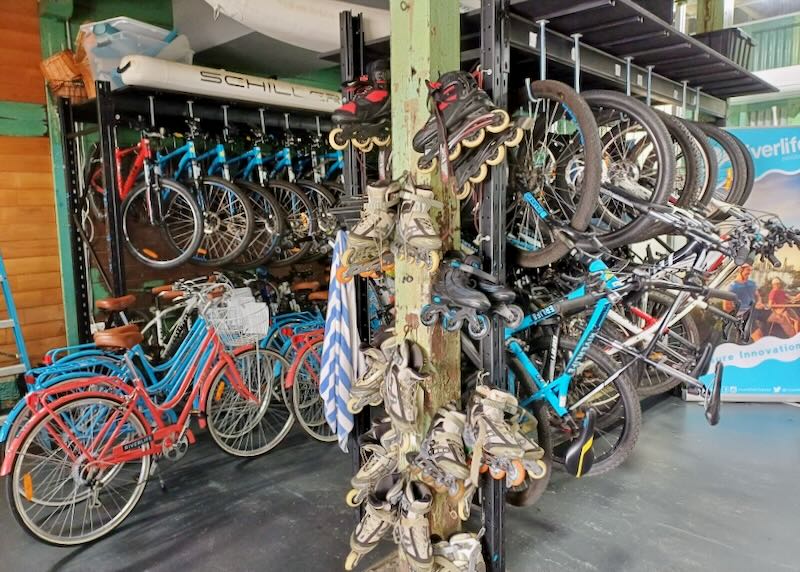 lots of bikes and rollerblades hang on walls waiting to be rented.