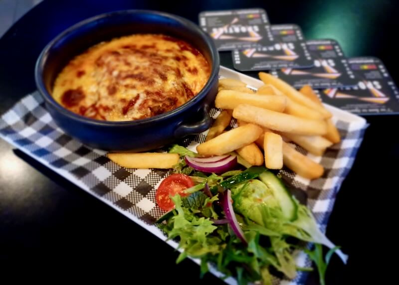 A plate with a crock of hot cheese and fires and salad.