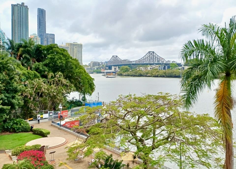 A view from high up of a river, palm tree, bridge, and skyscrapers