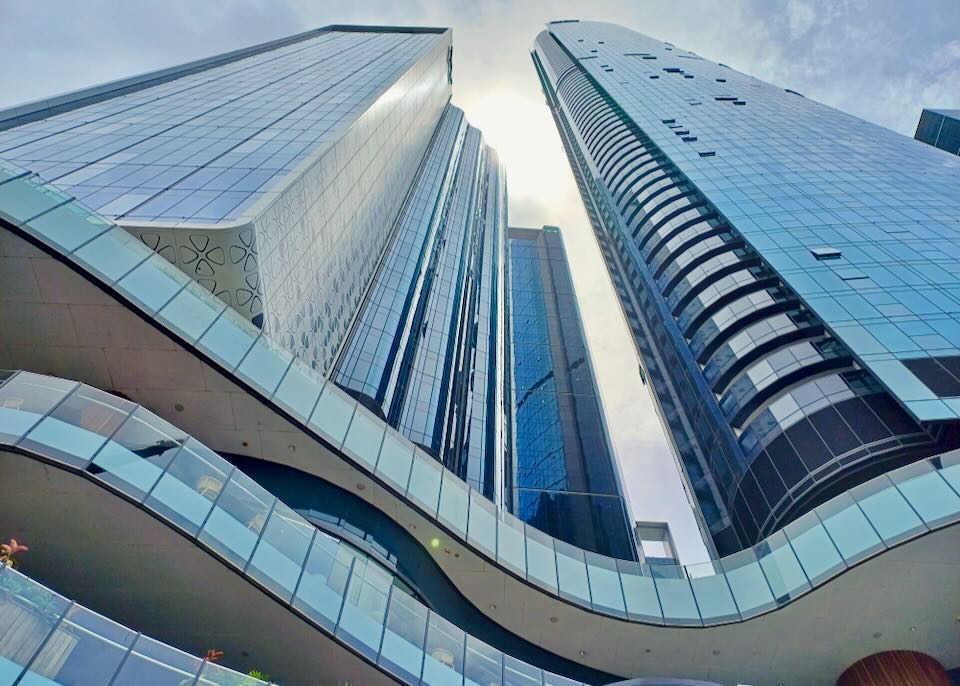 A view straight up to the sky of two blue glass towers.