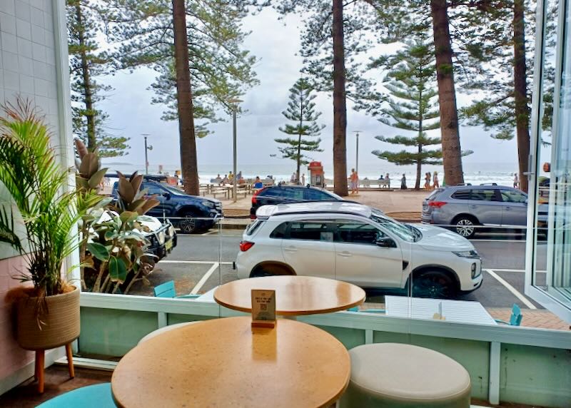 A table sits next to a large window next to a beach.