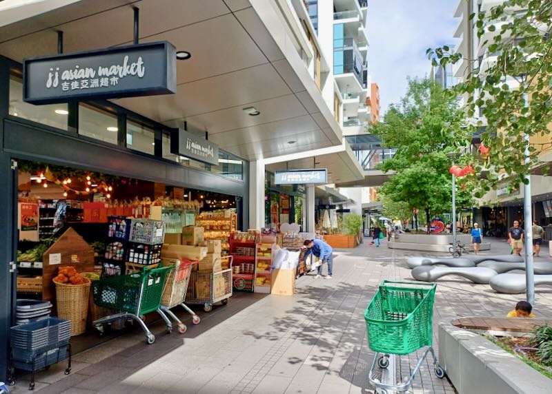 An asian food market with the front doors wide open has crates of food.