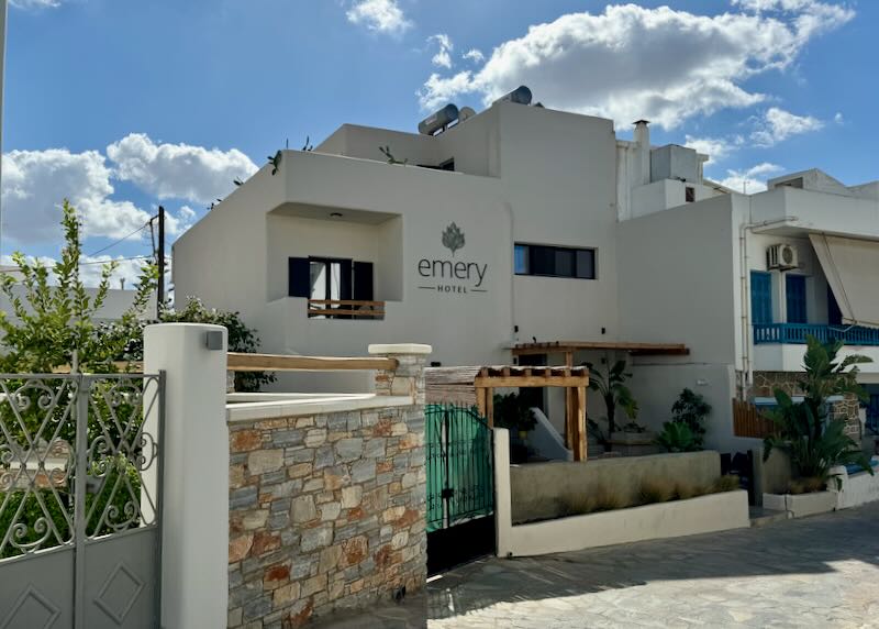 View of a Cycladic-style hotel with guest terrace in the front, on a quiet city street 