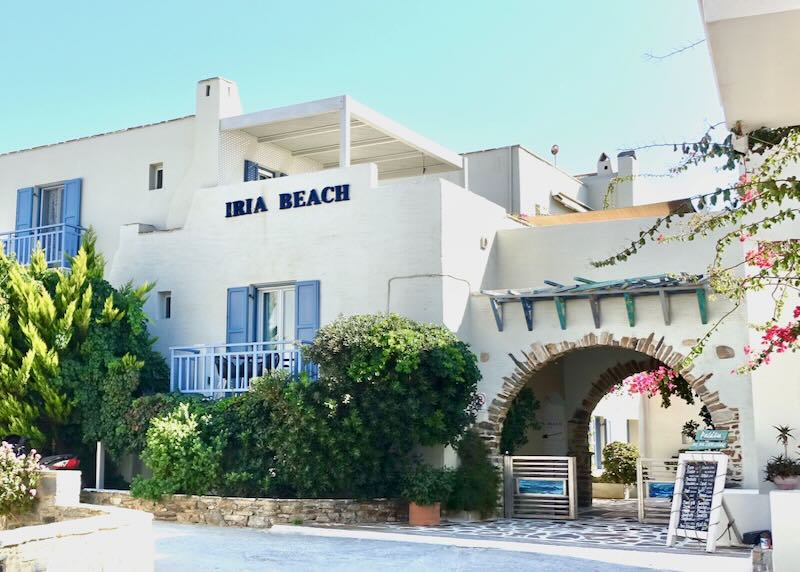 White, Cycladic-style hotel with blue shutters on a sunny day