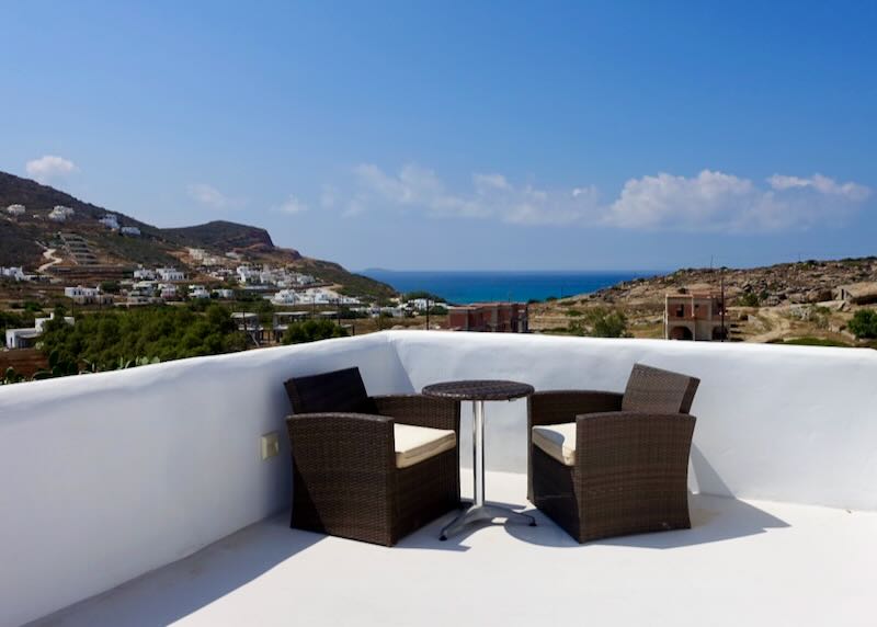 Two chairs and a table on a terrace overlooking the mountainside to the sea 