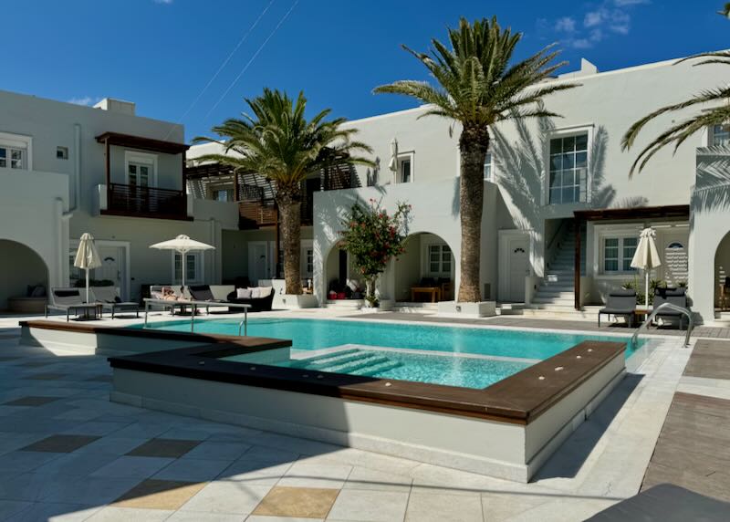 Hotel swimming pool courtyard with palm trees and sun loungers.