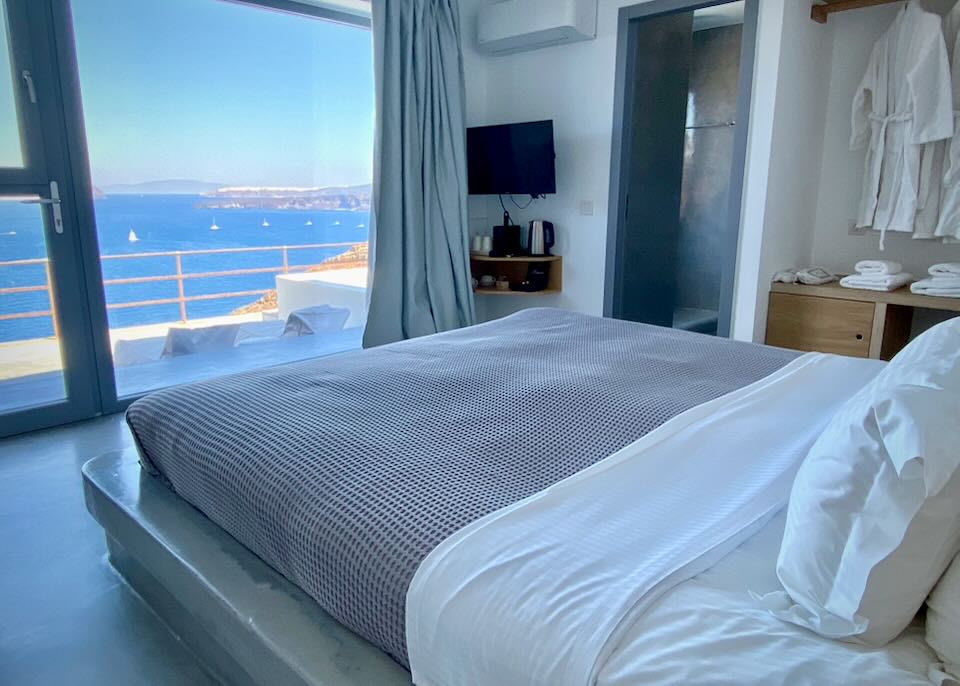 View over a hotel bed out a large window to the sea.