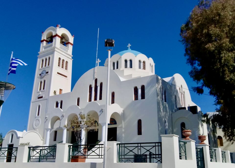 White church with blue domes against a blue sky.