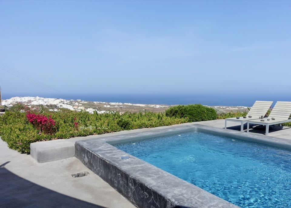 View over a small plunge pool to the town of Oia in Santorini.