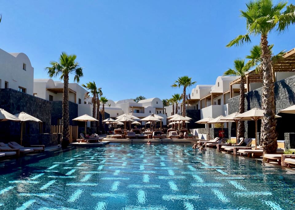 Hotel swimming pool surrounded by palm trees and sun loungers.