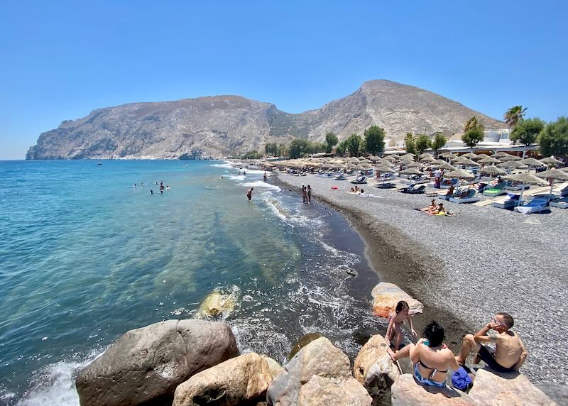 View up a pebbly beach toward mountainous foothills.