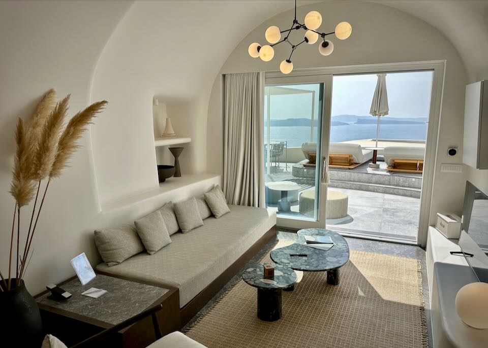 Hotel living room suite with domed, cave-like ceiling and open doors leading to a sea-view balcony.