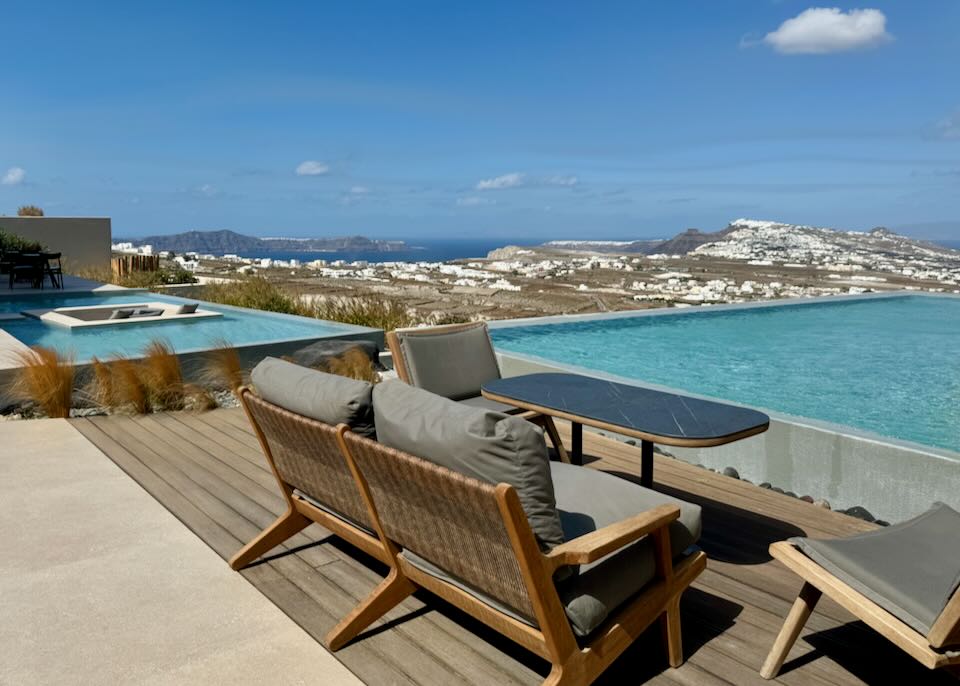 View from a hotel swim deck over the island of Santorini on a sunny day.