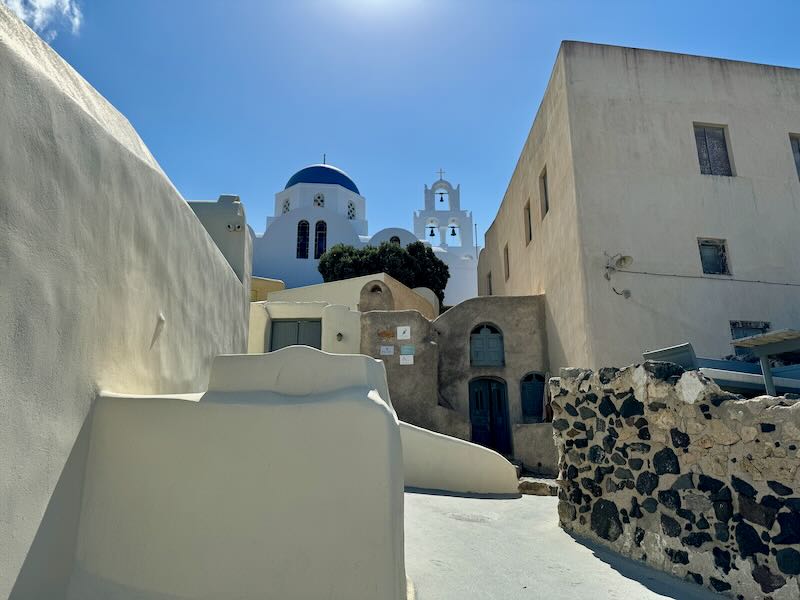 View up a narrow stone path in a traditional Greek village with a church at the top