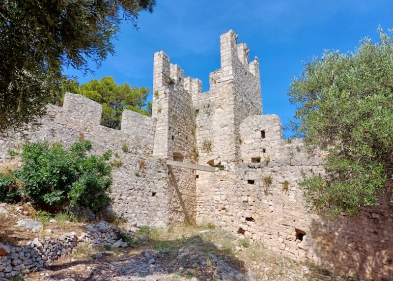 An old stone fortress sits with trees.