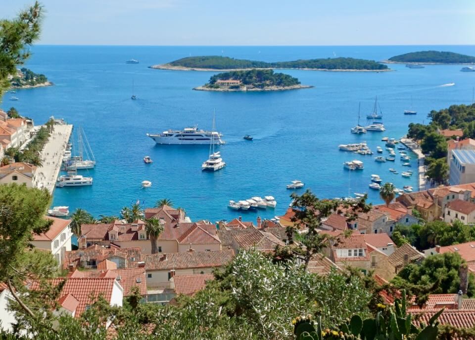 A view from high up on a hill of the ocean, small islands and a town with red shingled roofs.