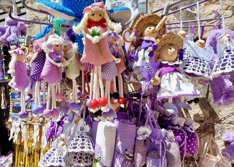 Purple and red small dolls hang on a sales rack.