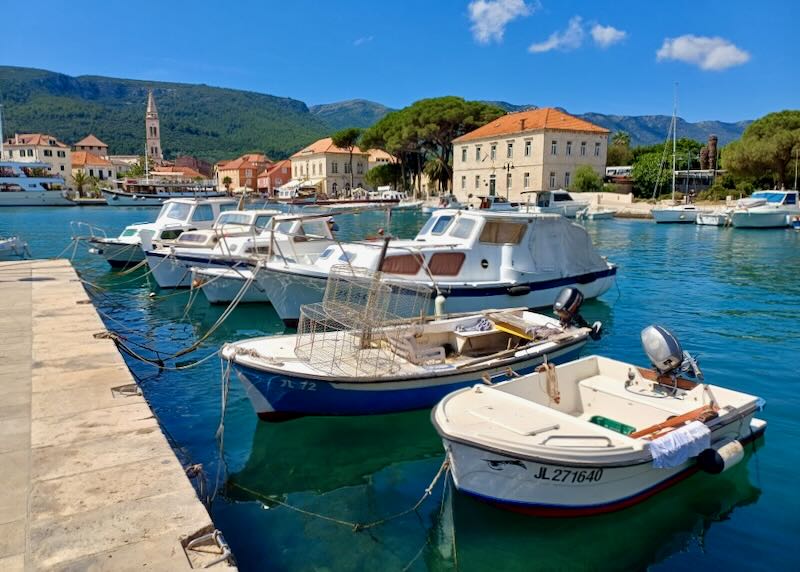 Small boats sit tied to a stone pier.