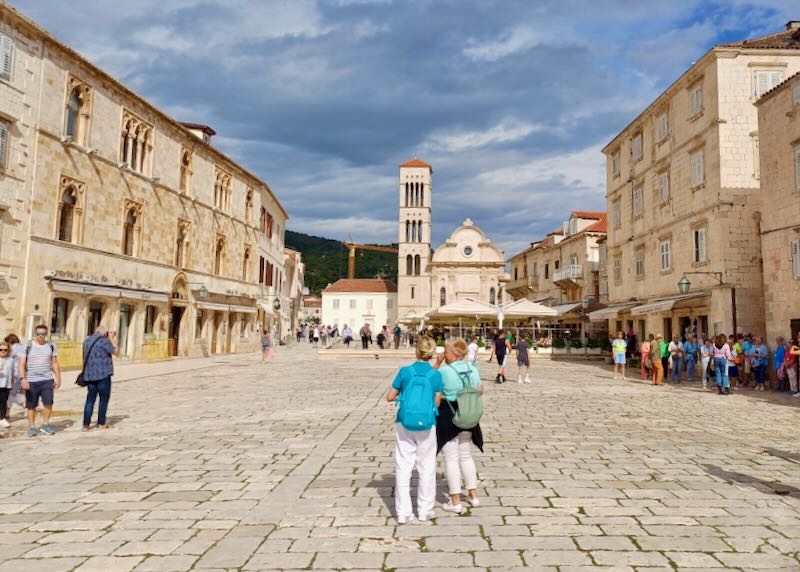 Tourists stand in a sun-bleached square.