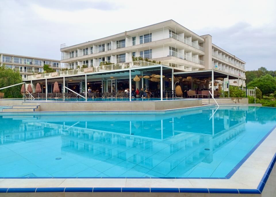 A large blue pool sits next to a restaurant.