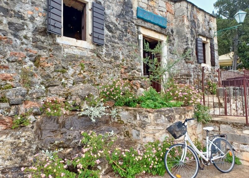 A bike leans against a stone wall outside a restaurant.