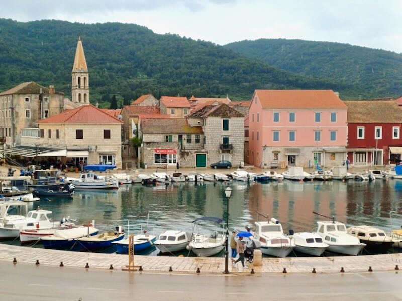 Beige stone buildings surround a small marina.