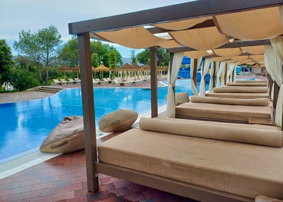 Cushioned lounge chairs line a blue pool at the end of a blue waterslide.