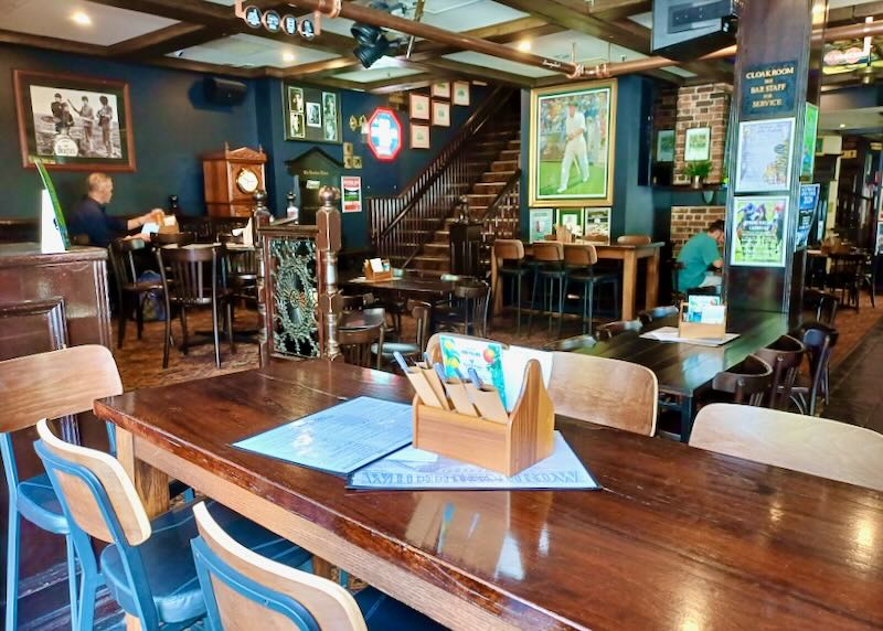 A dark wood bar with dark wood tables and dark green walls.