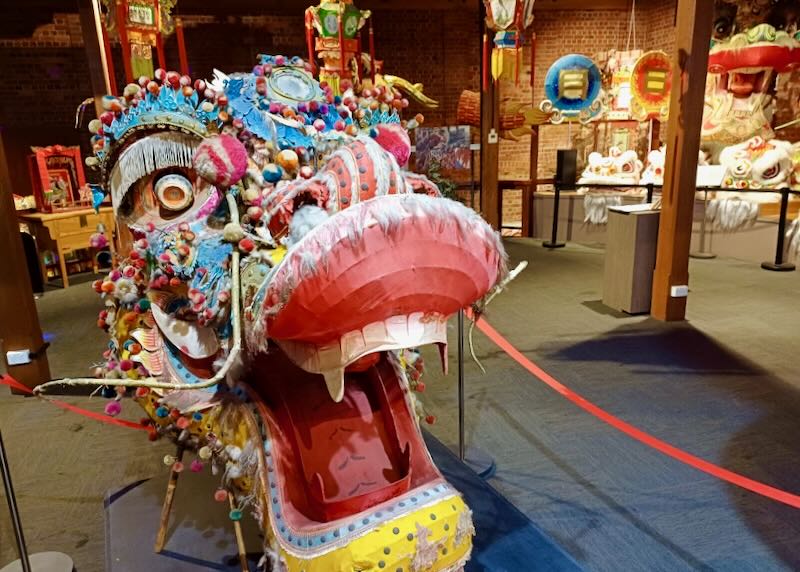 A large colorful Chinese dragon head sits on display at a museum.