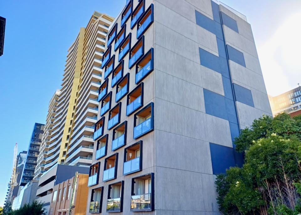 A tall building has balconies recessed into the building and outlined in black.